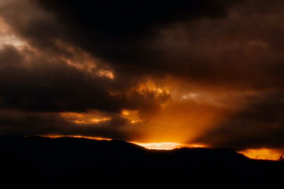 Landscape of a sunset behind mountains and clouds